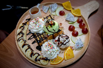 Fruit honey toast. dessert on the wood plate that is Toast and ice-cream top with strawberry and syrup dip