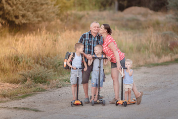 Family walk on scooters with his wife and children on the village road near Volgograd area