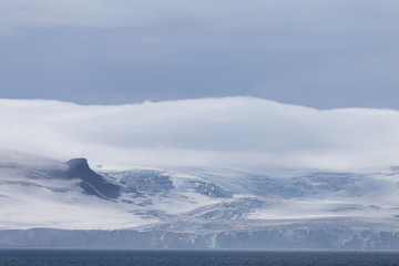 Fototapeta na wymiar Wind and clouds sweep over this mountain in Antarctica.