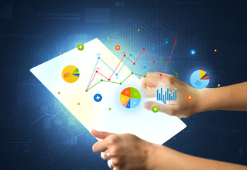Hands touching a glass-like tablet with charts