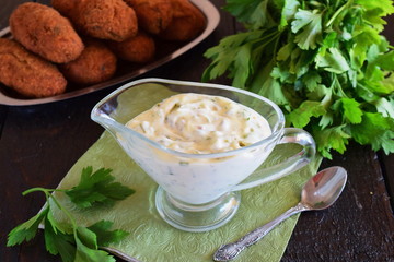 Tartar sauce in a gravy boat on a wooden surface