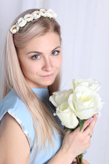 Obraz na płótnie Canvas Beautiful young blonde woman with clean skin and flower wreath in her hair on grey background, Keep flowers