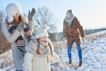 Eltern und Tochter spielen im Schnee - obrazy, fototapety, plakaty