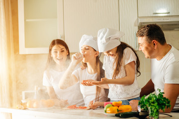 family making Christmas cookies and having fun. Mother sifts the flour