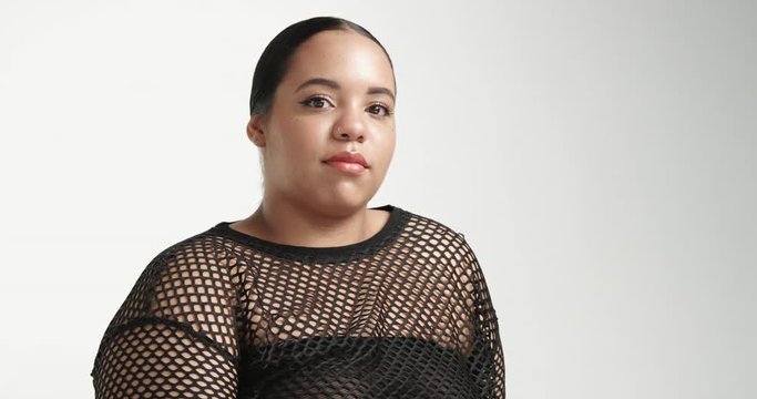 Sitting large curvy African American girl wearing a black fishnet top isolated on white. ideal skin, pretty smile portrait