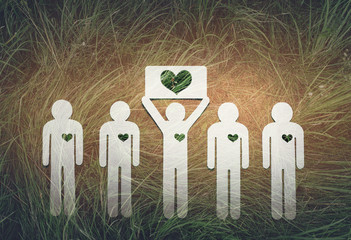 Paper people on green grass on bright background. Greenpeace, a symbol of the heart from the grass....