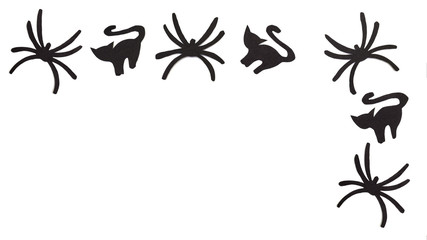 Silhouettes of black cats and spiders carved out of black paper are isolated on white