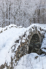 Old arch bridge with snow in a winter landscape