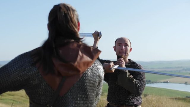 Two warriors Viking are fighting with swords in the meadow.