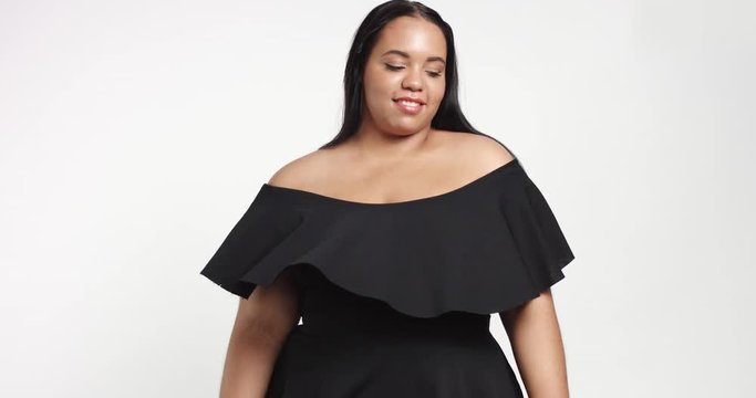 Confident strong young plus size African American model wearing a black short twirly dress flirting with camera isolated on white