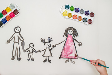 The child's hand paints a happy family