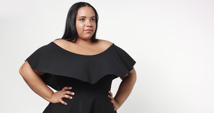 Confident strong young plus size African American model wearing a black short twirly dress flirting with camera isolated on white
