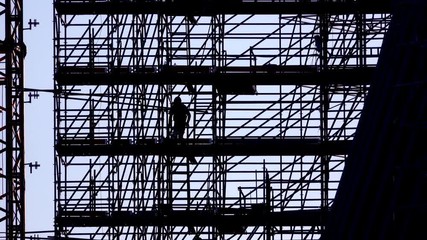 silhouette of workers going down scaffolding stairs, leaving work, ends the working day at building construction