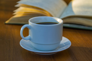 Cup of coffee and book on wooden table