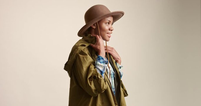 Portrait of an attractive young African woman dressed in safari hat, blue and white plaid shirt and khaki parka isolated on white
