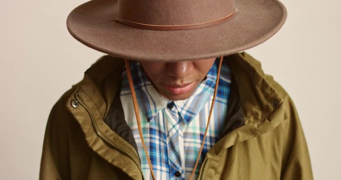 Portrait of an attractive young African woman dressed in safari hat, blue and white plaid shirt and khaki parka isolated on white