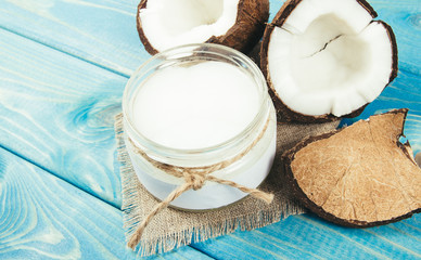 Coconut oil and fresh coconuts on a wooden table.