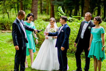 Newlyweds, groomsmen and bridesmaids pose together in a summer park