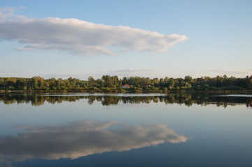 Naklejka na ściany i meble Panorama landscape with a forest and clouds reflecting in water of river Daugava. There is a cottage with red roof in the center