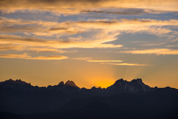 Sunset over the Alps. Colorful sky, high altitude mountain peaks with glaciers, Massif des Ecrins National Park, France. Telephoto view from distant.