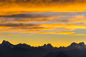 Sunset over the Alps. Colorful sky, high altitude mountain peaks with glaciers, Massif des Ecrins National Park, France. Telephoto view from distant.
