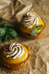 Lemon pie on the table with citrus fruits. Traditional french sweet pastry tart. Delicious, appetizing, homemade dessert with lemon cream. Copy space, closeup. Selective focus. Toned