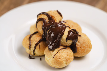 profiteroles covered with black chocolate on plate closeup