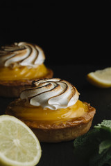 Lemon pie on the table with citrus fruits. Traditional french sweet pastry tart. Delicious, appetizing, homemade dessert with lemon cream. Copy space, closeup. Selective focus. Toned