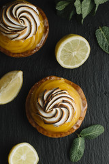 Lemon pie on the table with citrus fruits. Traditional french sweet pastry tart. Delicious, appetizing, homemade dessert with lemon cream. Copy space, closeup. Selective focus. Toned