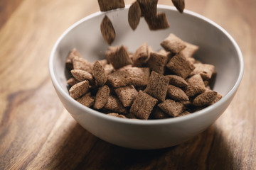 chcolate cereal pillow falling into white bowl on table