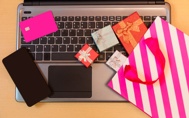 Gift boxes, shopping bag, credit card and smartphone on laptop keyboard. Online shopping concept.
