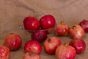 Ripe red pomegranates in a glass bowl on a brown burlap