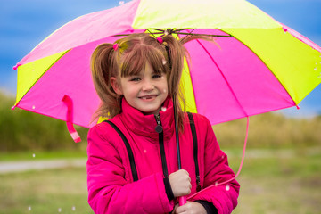 Happy child girl laughing with an umbrella in the rain in autumn day