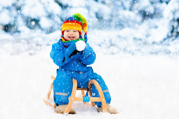 Fototapeta na wymiar Boy on sleigh ride. Child sledding. Kid with sledge