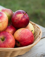 Fresh red yellow apples  in wicker plate on wooden table. Concept for seasonal fruits, autumn harvest and agriculture.