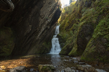 Small hidden waterfall in the forest in the cleft of the rock