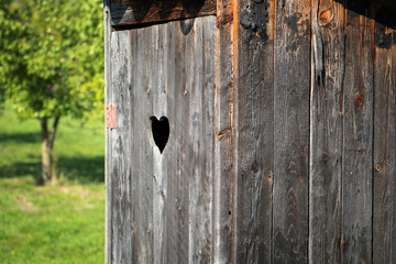 Wooden outdoor toilet with heart on the door.