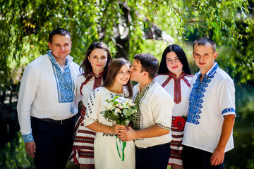 Newlyweds, groomsmen and bridesmaids pose together in a summer park