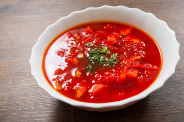 Bowl of red beetroot soup on a wooden background.