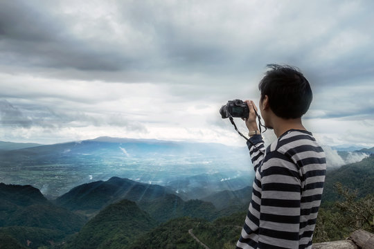Young man traveler photographing mountain and sunset, Chiangmai Thailand. Alone travel concept.