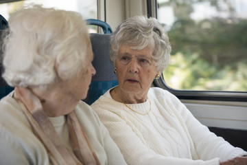 Two senior women talking together on a train 