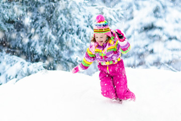 Child playing with snow in winter. Kids outdoors.