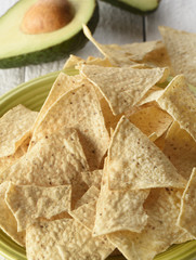 Green plate full of tortilla chips on a white background