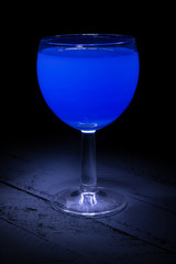 blue cocktail in a glass on a black background