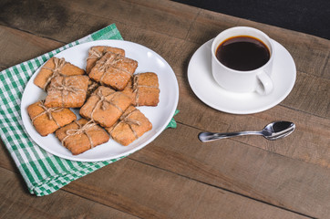 Black coffee in a white cup on a green napkin and homemade cookies.