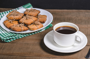 Black coffee in a white cup on a green napkin and homemade cookies.