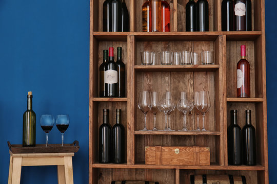 Wooden storage stand with wine bottles and glasses indoors