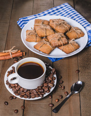 Black coffee in a white cup on a blue napkin and homemade cookies.