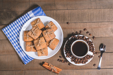 Black coffee in a white cup on a blue napkin and homemade cookies.
