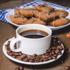 Black coffee in a white cup on a blue napkin and homemade cookies.